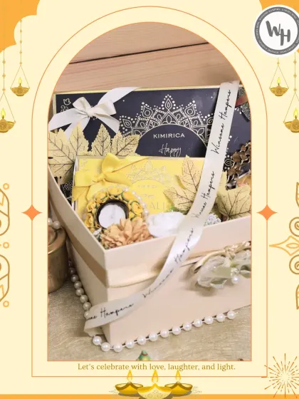 A luxurious collaboration with Kimirica, this Diwali hamper is housed in a sophisticated cream-colored gift box. It combines premium skincare products with festive elements like a decorative candle holder and artificial flowers, tied with a custom ribbon.