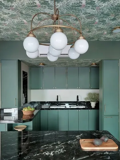 The chandelier above the island adds a touch of glamour and provides warm ambient lighting, contrasting beautifully with the rustic feel of the wooden island and green cabinets.