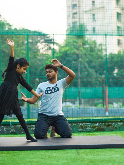 A young girl practices her gymnastic poses with a coach. I focus on making learning fun while building discipline and grace.
