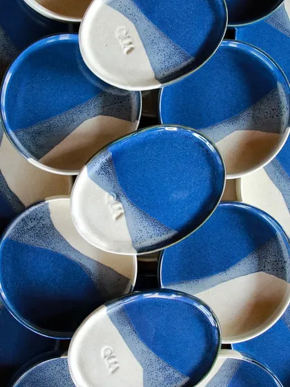 A flat lay of the sea-inspired plates, showing the beautiful spray effect of the glazes. Each plate is slightly different, yet they form a cohesive set.