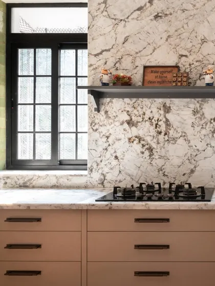 This angle highlights the continuous marble backsplash and the simple, elegant hardware on the muted cabinets. Every detail is considered to maximize the sense of space and calm.