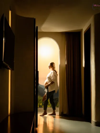A silhouette of the mother-to-be standing on a balcony, looking out at the mountains. A beautiful, contemplative moment.