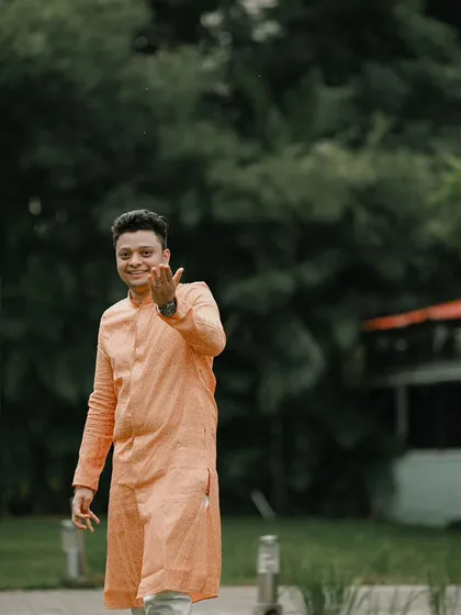 A happy and candid shot of the groom, his expression full of joy as he welcomes guests to his reception.