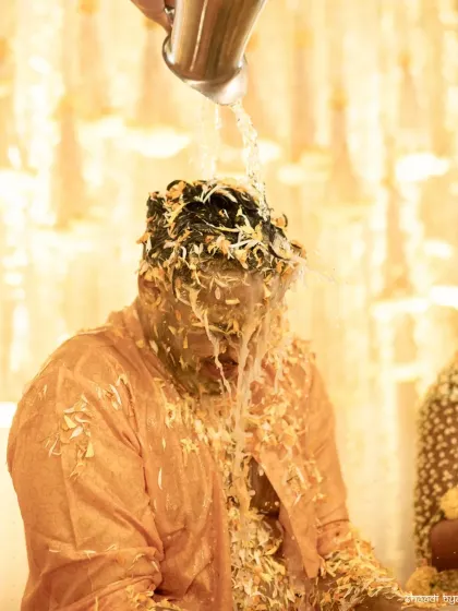 A dramatic shot of the groom getting drenched with water during the haldi, a fun ritual to wash it all off.