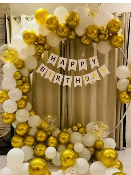 A classic birthday setup with a circular frame and a gold and white balloon arch. The decoration includes a "Happy Birthday" banner.