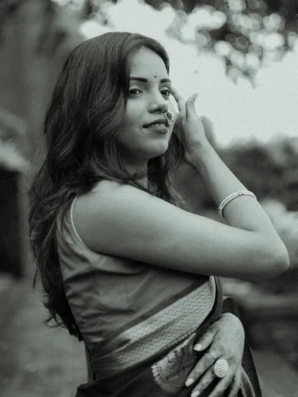 A candid black and white portrait. The model adjusts her hair with a gentle expression, creating a natural and spontaneous moment that feels authentic and unstaged.