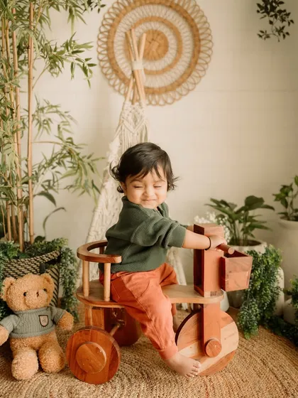 A happy moment playing with the wooden tricycle prop in the studio.