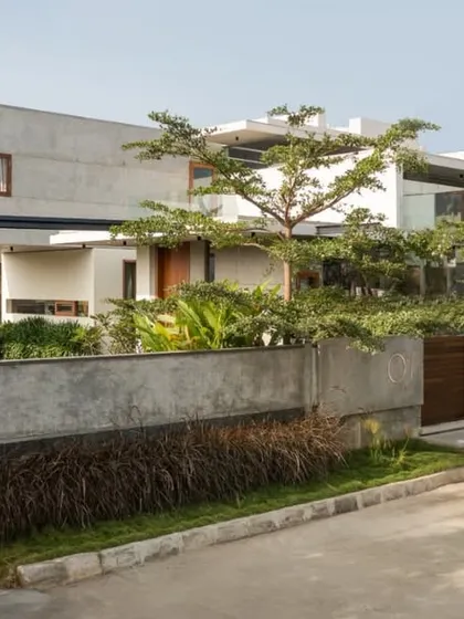 Viewed from the street, The Quarry House presents a layered facade of concrete, glass, and greenery. The boundary wall, constructed from the same concrete, integrates seamlessly with the main structure and the thoughtfully designed landscape.