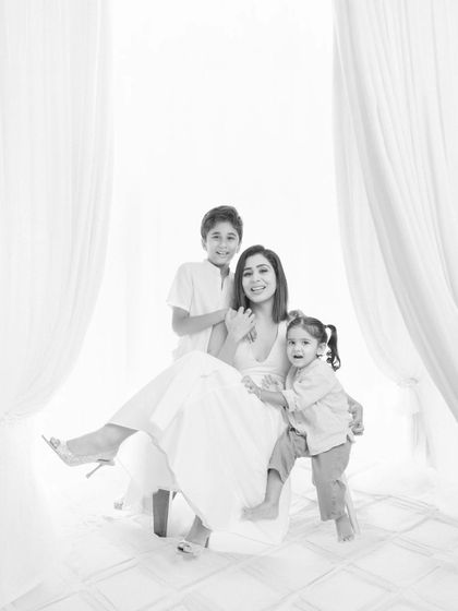 A mother sits with her two children in this joyful black and white studio portrait. The best days are worth remembering, and this image captures the love and playful energy of a mother with her son and daughter.