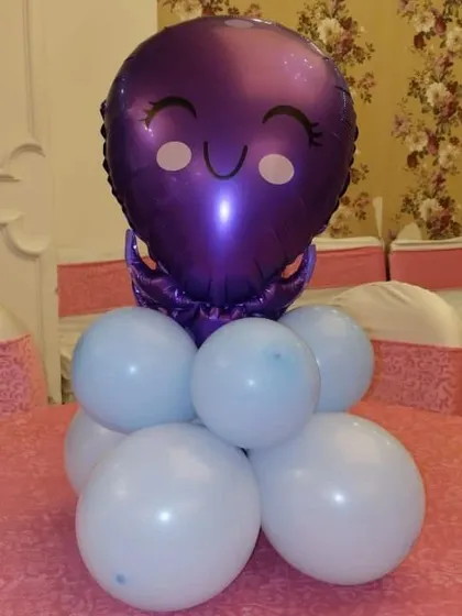 A simple and adorable balloon table centerpiece. This piece features a purple octopus foil balloon on a base of light blue balloons, perfect for an underwater or mermaid-themed party.