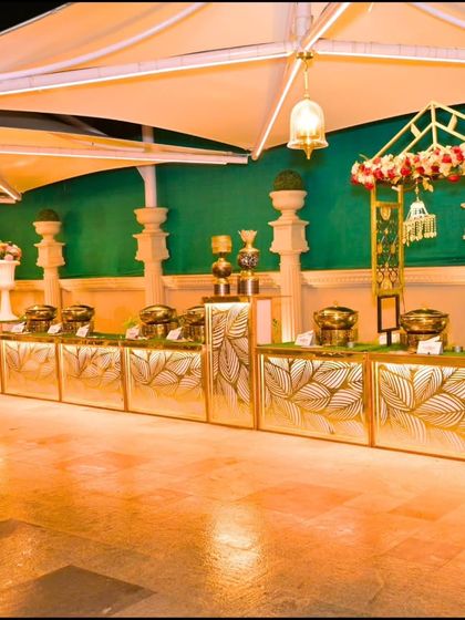 An elaborate and elegant buffet setup for a wedding reception. I believe that even the food service area should be beautifully decorated to match the event's aesthetic, using custom counters and floral arrangements.