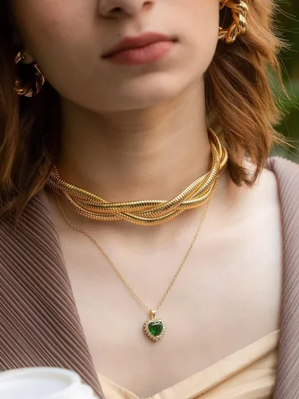 A close-up of our layered necklace look. The chunky rope choker paired with a delicate emerald heart pendant creates a perfect balance of bold and elegant.