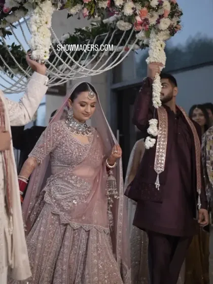 The bride, Ashima, making her graceful entrance under a 'phoolon ki chaadar' decorated with pearls and fresh flowers.