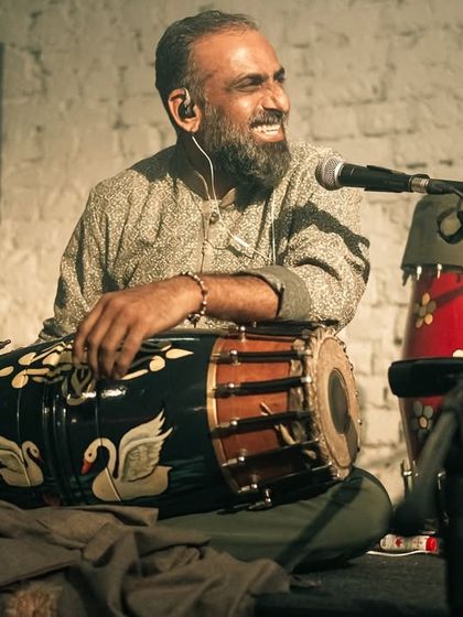 Pramath Kiran, smiling and in his element, playing the mridangam. His joy for music is evident in every beat he plays.