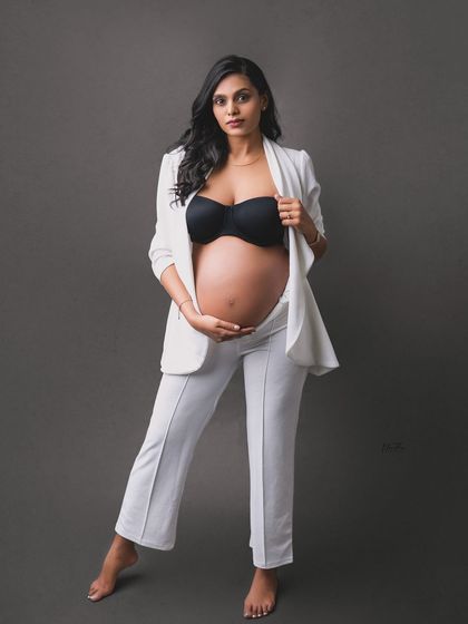 A bold and confident maternity portrait. The mom-to-be wears a stylish white suit, showing that maternity fashion can be powerful and modern.