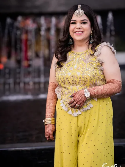 A full-length shot showing how the bouncy curls add to the overall festive and joyful vibe of a Mehendi celebration. The hair moves beautifully and holds its shape throughout the event.