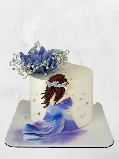 A delicate and artistic maternity cake celebrating the beauty of motherhood. The design features a hand-painted figure and soft floral touches.