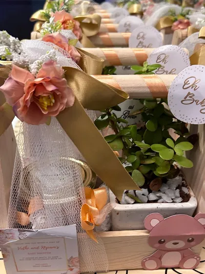 Thoughtful party favors for a baby shower. These cute gift baskets include a small plant and other goodies, beautifully packaged to thank the guests.