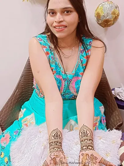 A happy client with her custom sister-themed mehndi. The design includes portraits and lotus motifs, all done with natural henna for a beautiful, lasting stain.
