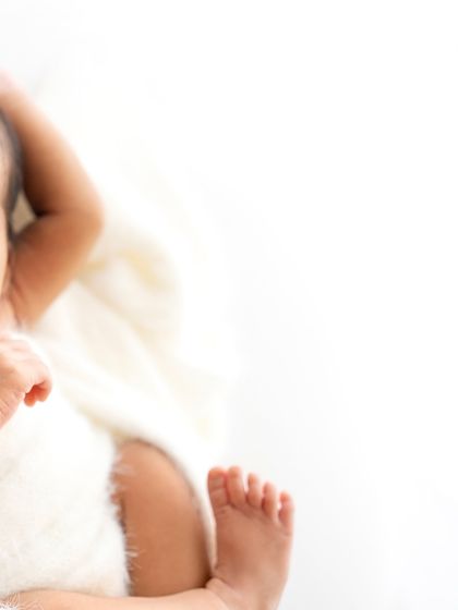 Another artistic, minimalist detail shot. You can just see the baby's face, hand, and foot, creating a sense of peace and tranquility.