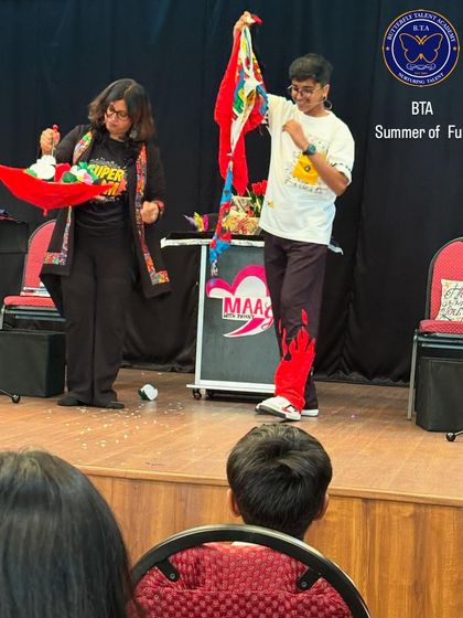 An instructor and a student perform a magic trick together on stage. These interactive moments build confidence and create unforgettable memories for our campers.