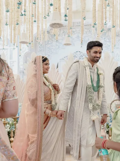 A quiet moment between the couple as they walk down the aisle, hand in hand. The soft pastel colors of the decor create a serene and romantic atmosphere.