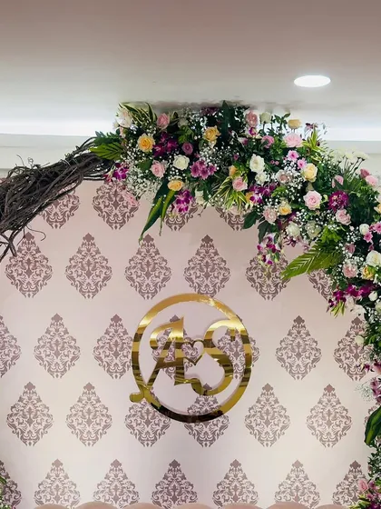 A close-up of the floral twig arch and the custom acrylic monogram featuring the couple's initials. This personalized element adds a unique and meaningful touch to the engagement backdrop.