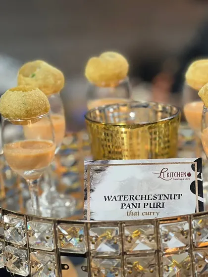 A creative fusion appetizer: Pani Puri shells filled with a waterchestnut and Thai curry mixture, served in elegant glasses.
