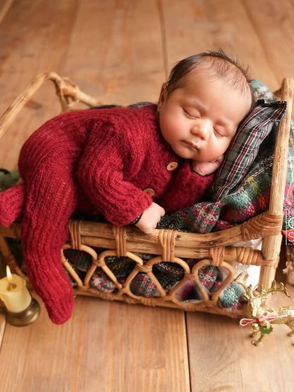 A sleeping newborn in a wicker basket bed, part of a warm, candlelit Christmas scene. This image evokes a sense of peace and holiday magic.