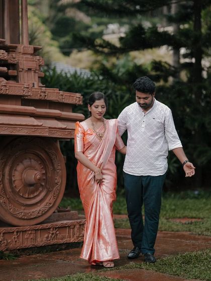 A candid moment by the Hampi stone chariot replica, blending love and heritage.