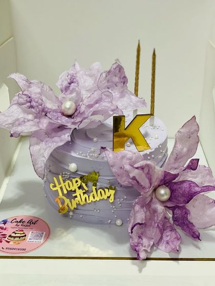 An artistic cake featuring delicate, edible fantasy flowers in a beautiful lavender shade.