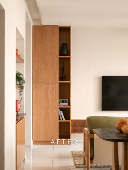 An 'after' shot showing the bright and welcoming living space. The tall, built-in wooden shelving unit adds verticality and storage, while the sage-green sofa provides a soft pop of color.