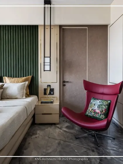 This bedroom design demonstrates how subtle luxury can make a bold statement. Warm color tones on the walls are complemented by grey marble flooring and a striking red accent chair, creating a space that is both sophisticated and visually dynamic.