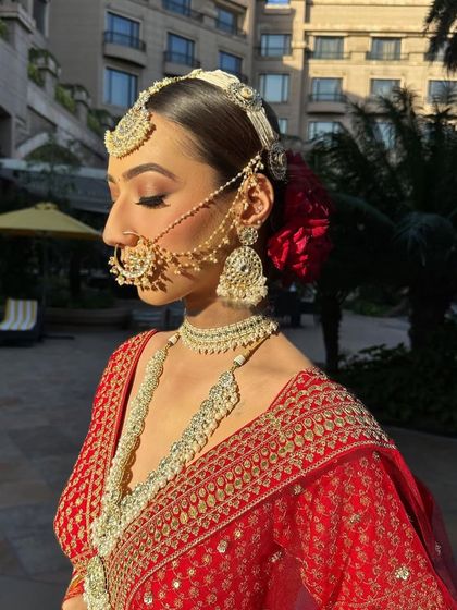 A side profile of this regal bride shows how the sleek bun, traditional passajewelry, and a single red rose come together to create an unforgettable look.