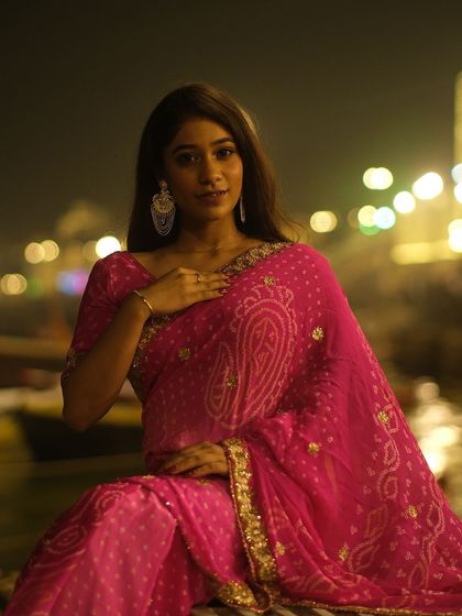 Glowing in pink against the bokeh of city lights on the Ganga. A beautiful portrait celebrating Dev Deepawali on the ghats of Banaras.