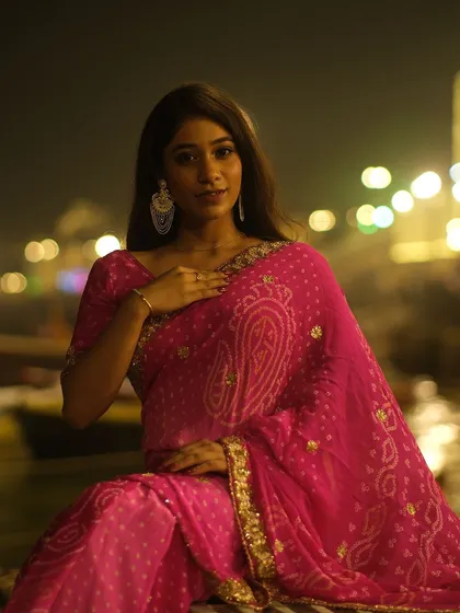Glowing in pink against the bokeh of city lights on the Ganga. A beautiful portrait celebrating Dev Deepawali on the ghats of Banaras.
