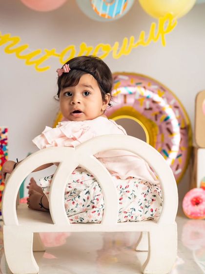 A quiet, curious moment amidst the party fun. This little one takes a seat on a miniature bench in our donut-themed setup.