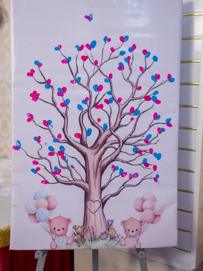 A close-up of a creative baby shower activity: a thumbprint guest book tree. Guests add their pink and blue thumbprints as 'leaves' on the tree, creating a unique and personal keepsake for the parents-to-be.