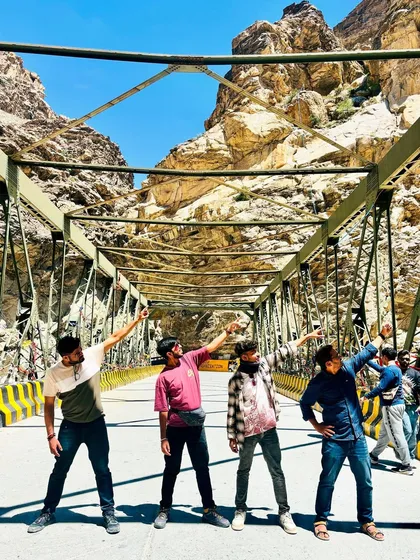 The group striking a pose on a bridge, pointing towards the adventure ahead. The raw, rocky landscape of Spiti is a character in itself on these trips.