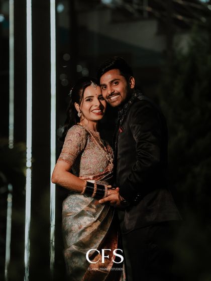 A smiling couple poses for a nighttime reception photo. The vertical lights in the background add a modern and stylish element to this happy portrait.