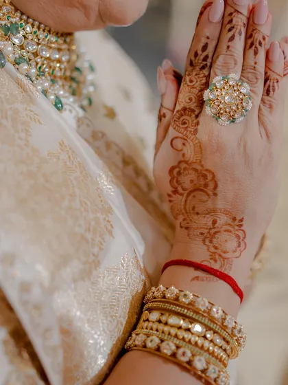 A close-up of the mother's hands, highlighting a stunning statement ring and delicate henna design. Every detail is thoughtfully curated to complete the overall look.