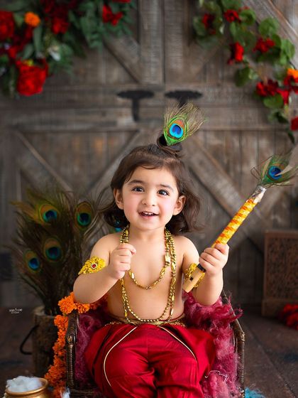 A joyful portrait of a little boy dressed as Krishna, holding a peacock feather.