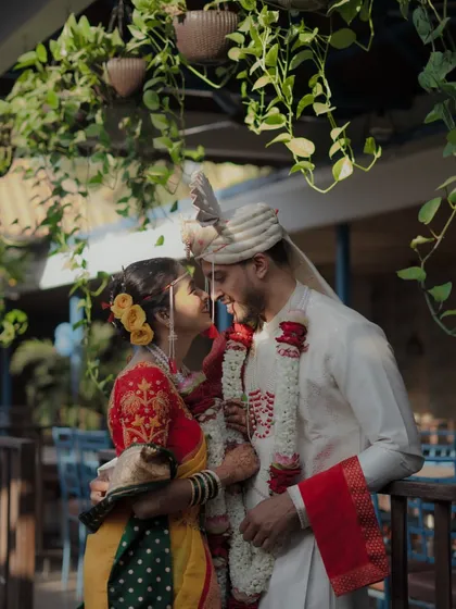 An intimate portrait of a Maharashtrian couple, lost in their own world. The lush greenery frames their love, highlighting the beautiful details of their traditional wedding attire.