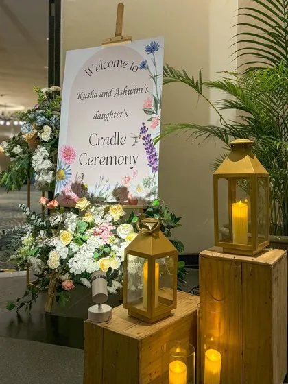 The entrance setup for the naming ceremony, combining rustic wooden boxes with elegant lanterns and florals.
