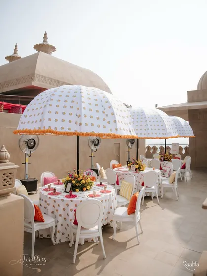 Outdoor seating under large, custom-printed umbrellas with marigold tassels. This setup provided shade and style, continuing the block-print theme throughout the venue.