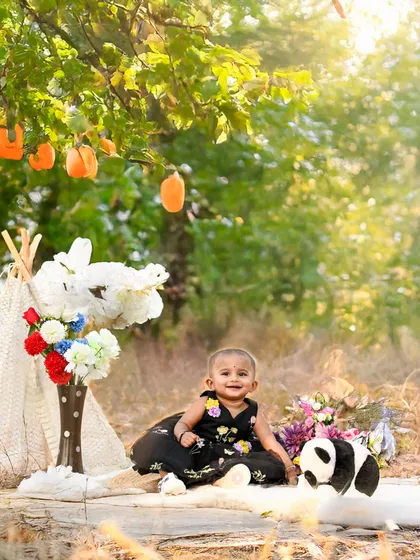 A whimsical outdoor setup with a teepee and props in a sunlit field. This is perfect for a boho-chic or adventure-themed toddler shoot.