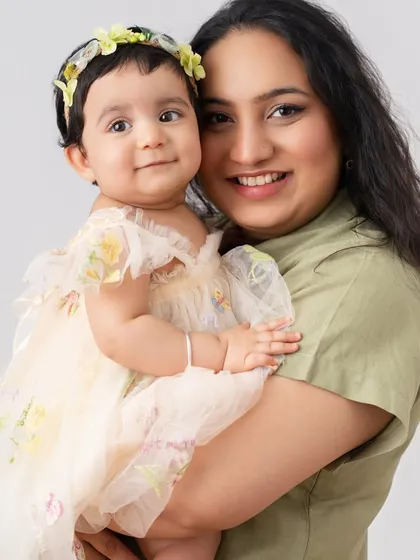 A mother's love shines in this beautiful portrait. Holding her daughter close, her smile is full of warmth and affection.
