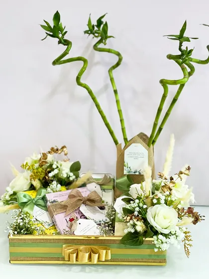 The complete eco-friendly hamper, showing the balance between the tall, spiraling bamboo and the low, lush floral arrangements. The natural color palette of greens, whites, and browns is calming and sophisticated.
