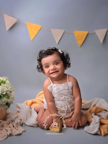 A beautiful, happy portrait of a sitter. The simple grey background and yellow bunting create a cheerful and modern look for her milestone photos.