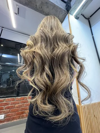 A stunning example of a full, long-haired balayage with cool blonde tones, styled into glamorous waves.